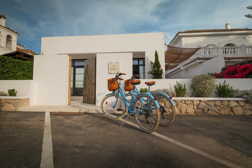 Fachada blanca de Casa Chica con dos bicicletas junto a la entrada