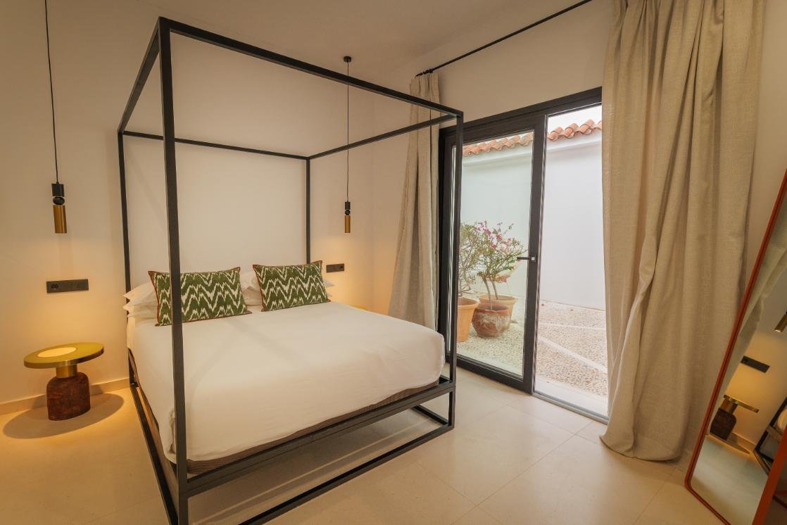 Dormitorio de Casa Chica con dosel y cojines verdes