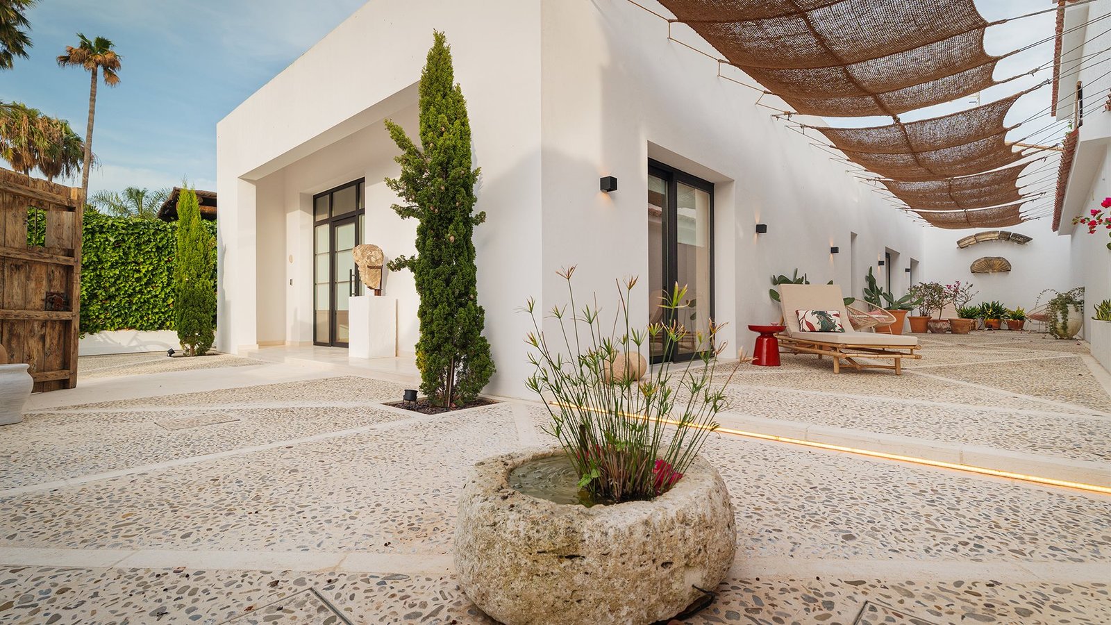 Patio blanco de Casa Chica, con plantas y una pérgola de sombra